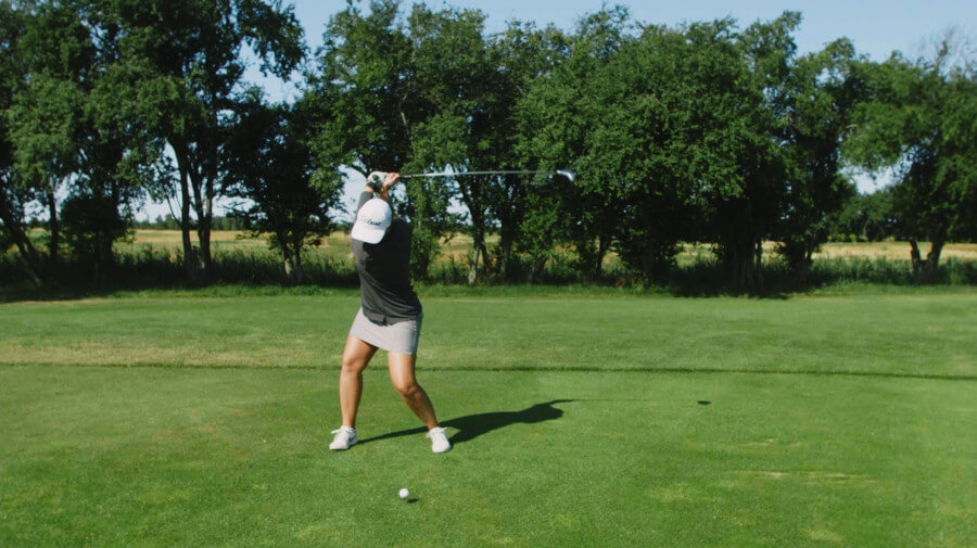 female golfer at top of the golf swing