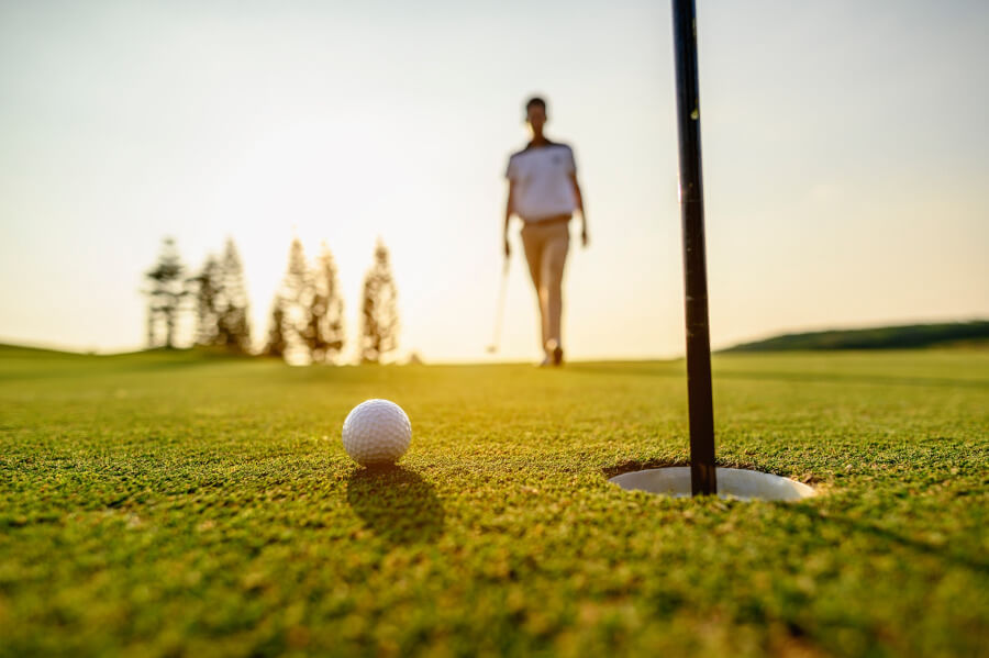 golf ball going to hole hit by golfer at golf course