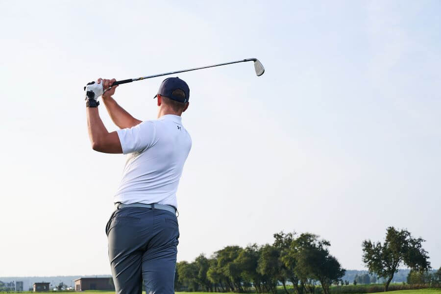 golf player on golf course hitting with iron