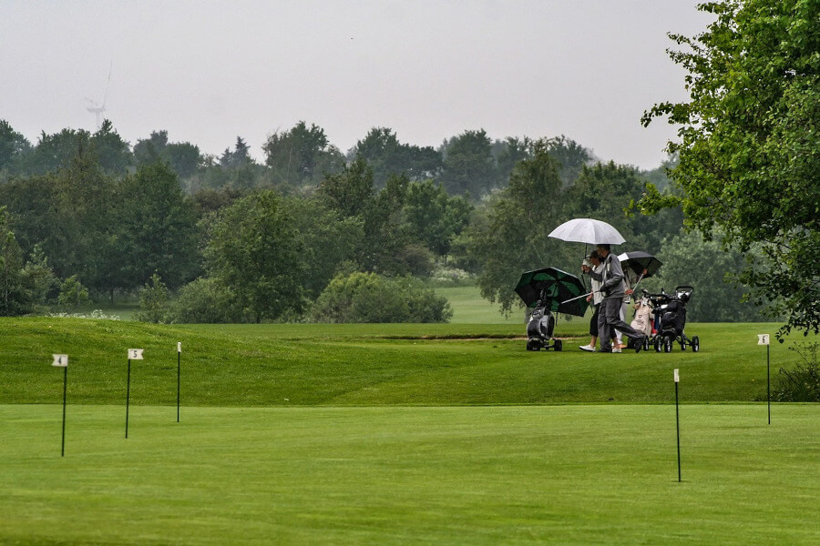 golf player on golf course while raining