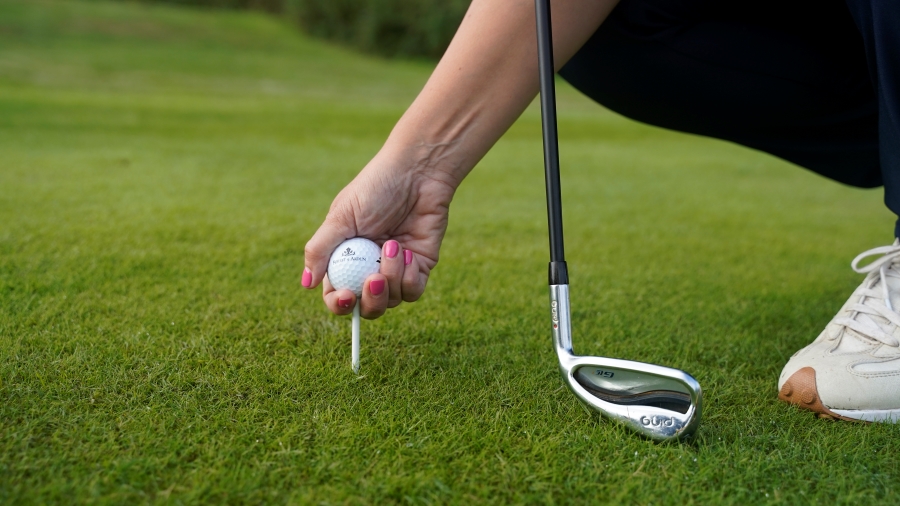 golfer putting ball on golf tee