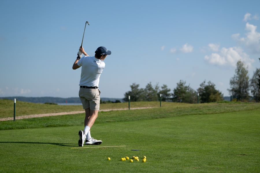 golfer training on course with alignment stick on ground