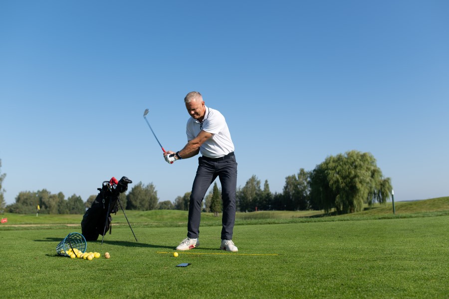 golfer training on golf course with bucket of golf balls