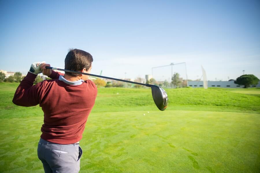man in red sweater holding a golf club