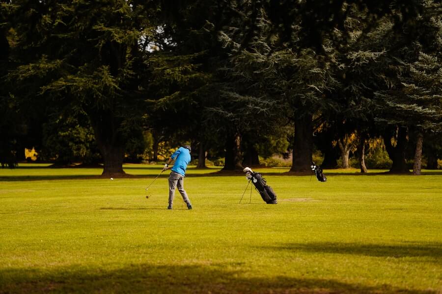 man playing golf on golf course hitting with iron