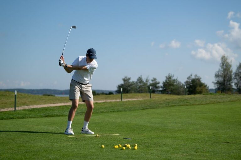 player on golf course training with HackMotion and alignment stick