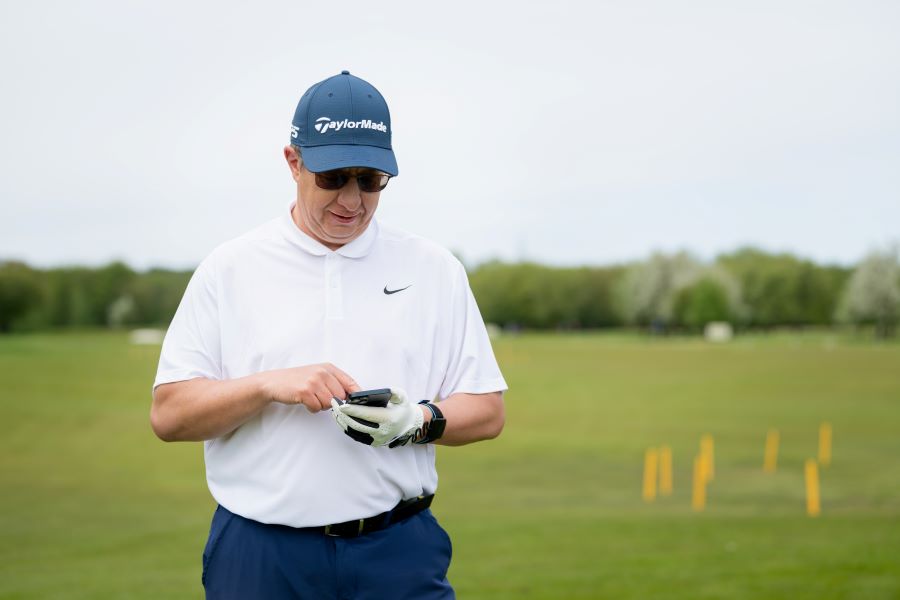 senior golfer on driving range using golf app