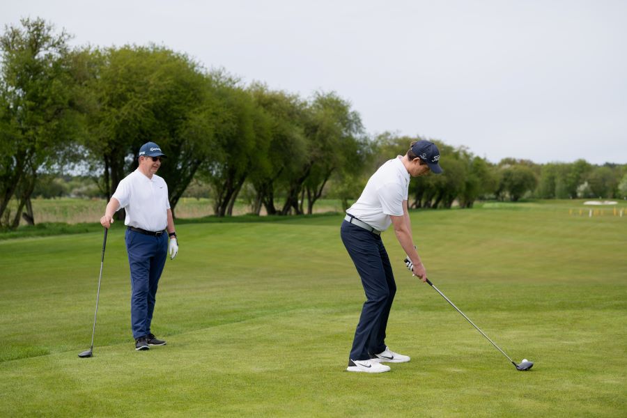 two golfers on golf course - one ready for driver shot